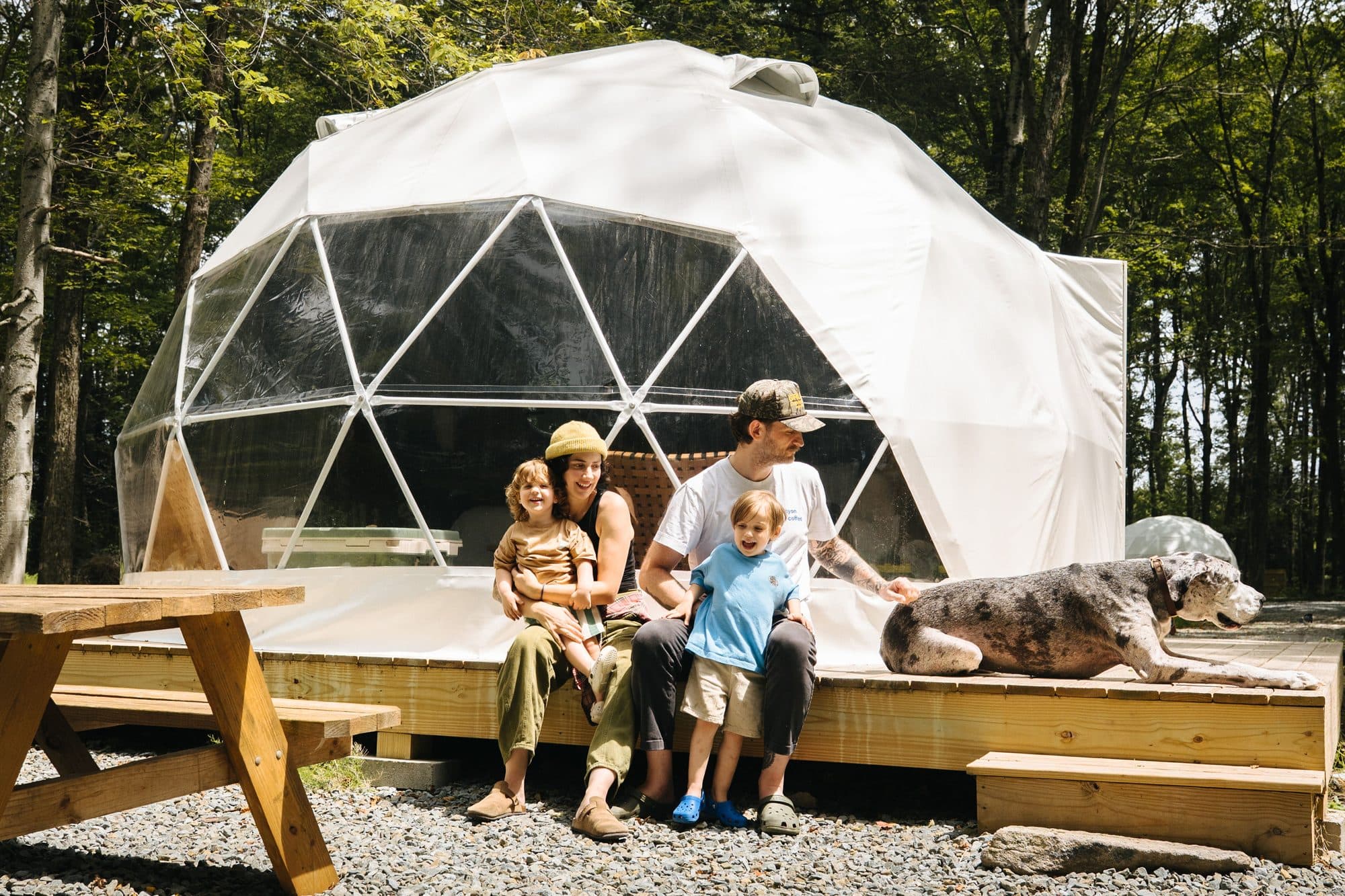 A family on the deck of a Ferncrest dome in the woods